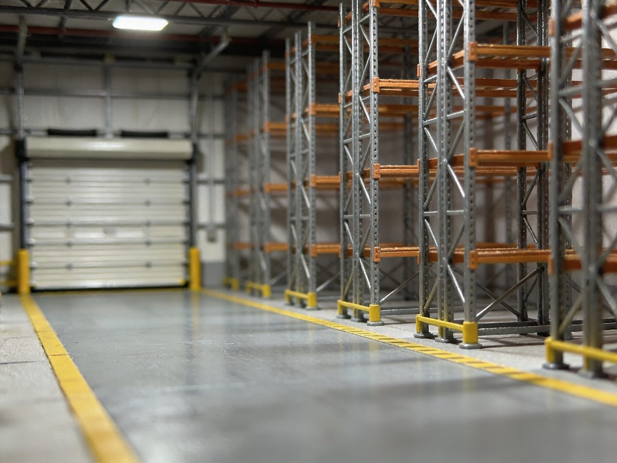 A warehouse bay with a high-build epoxy floor, steel racking and yellow safety lane striping